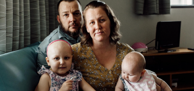 A little girl sits with her family in a Leukaemia Foundation accommodation unit